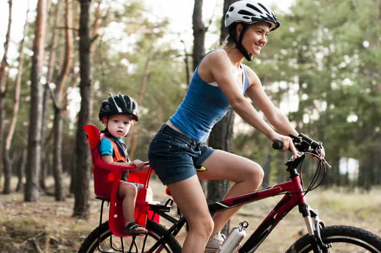 Mother riding on bicycle with young child in back